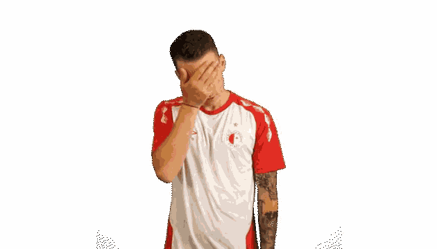 a man with his hands on his hips wearing a red and white umbro jersey