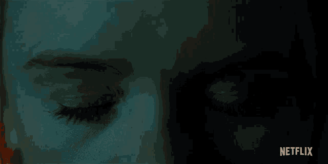 a close up of a woman 's eyes with red irises in a dark room .