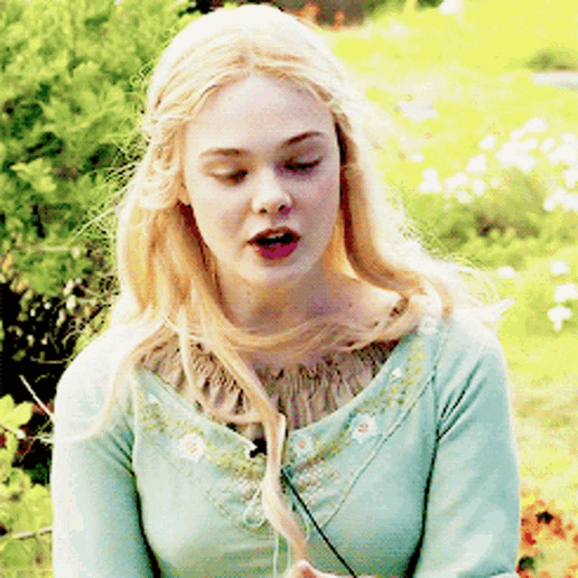a woman with blonde hair is wearing a light blue sweater