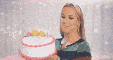 a woman is blowing out candles on her birthday cake .