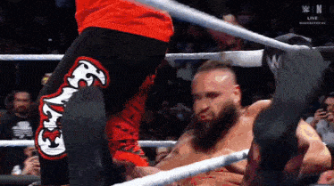 a man with a beard is wrestling another man in a ring with a crowd watching .