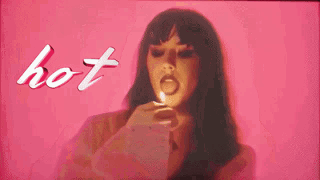 a woman is lighting a candle in front of a pink background that says hot