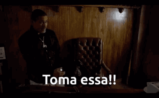 a man standing next to a chair with the words toma essa written on the bottom