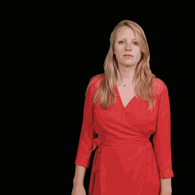 a woman in a red dress stands in front of a man 's hand