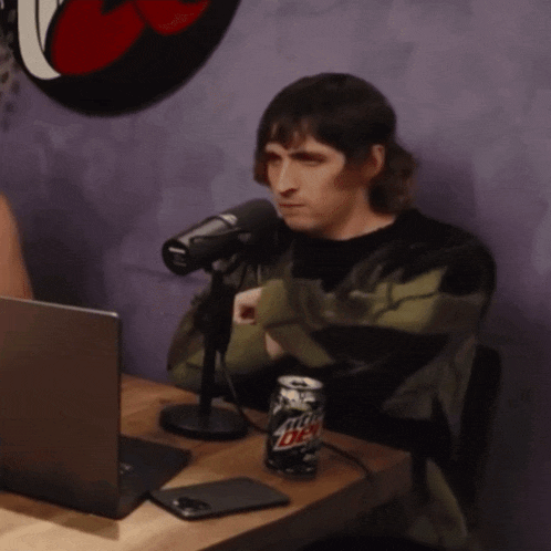 a man sits at a table with a can of mountain dew
