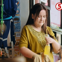 a woman in a yellow shirt is holding a bottle and a bag