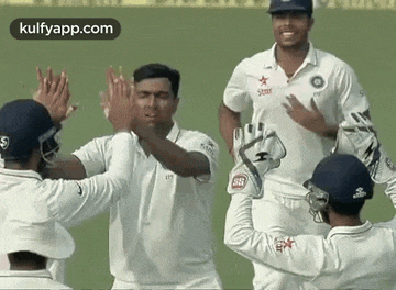 a group of cricket players are giving each other high fives .