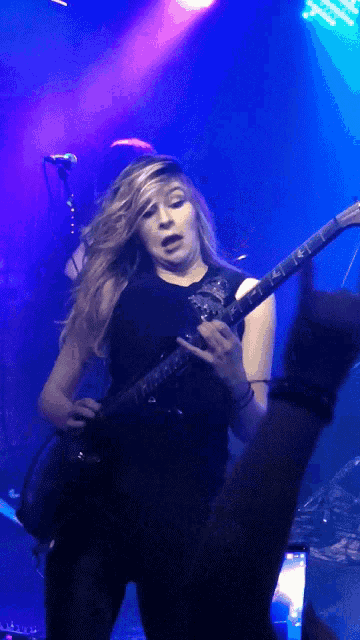 a woman playing a guitar in front of a microphone with a purple light behind her