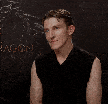 a man with his arms crossed is standing in front of a dragon poster