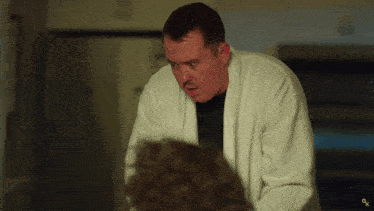a man in a white robe is standing in front of a microwave with the letter g on it