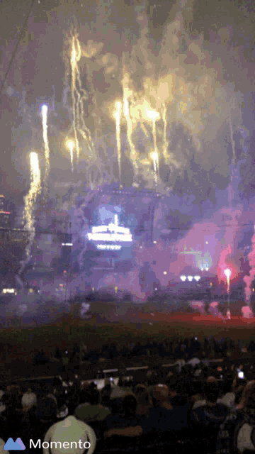 a crowd of people watching a fireworks display with the word momento on the bottom