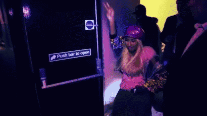a woman wearing a pink hat and a pink shirt is dancing in a dark room