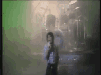 a blurry picture of a man singing into a microphone in front of a drum set .