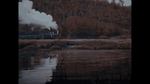 a train is going down the tracks next to a lake