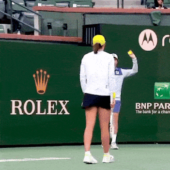 a tennis player stands in front of a rolex ad