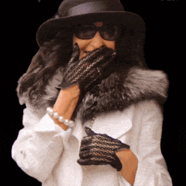 a woman wearing a hat and gloves covers her mouth