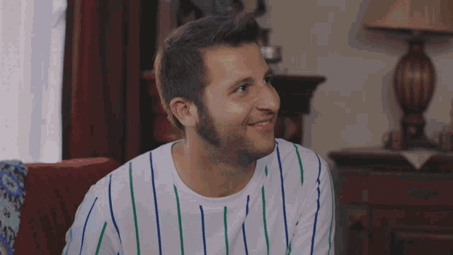 a man wearing a striped shirt is smiling in a room