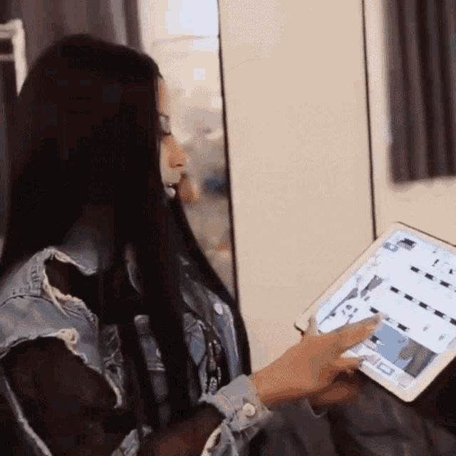 a woman with long black hair is using a tablet computer