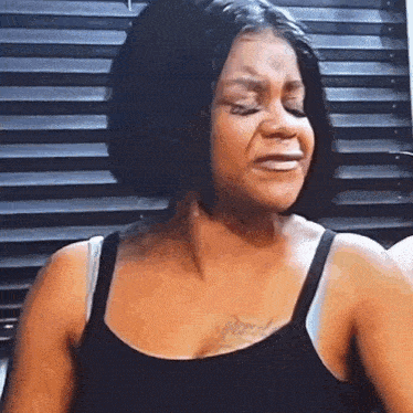 a woman is crying while wearing a black tank top .