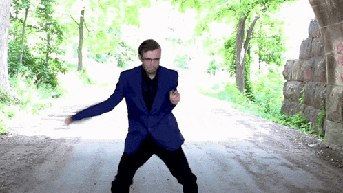 a man in a blue suit is dancing on a road