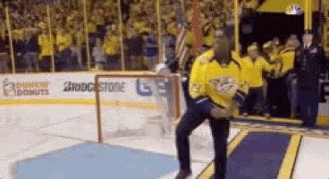 a man in a yellow jersey is standing on a hockey rink in front of a bridgestone sign