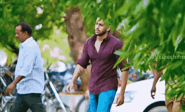 a man in a purple shirt is walking down a street
