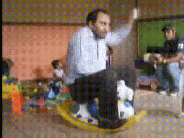 a man is sitting on a rocking horse with a soccer ball on it