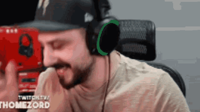 a man wearing headphones and a hat is smiling while playing a video game .