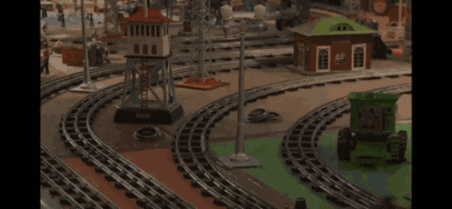 a toy train set with a green tractor going down the track
