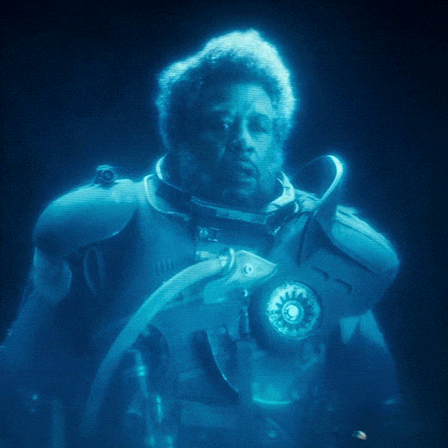 a man in a futuristic suit is glowing in a dark room