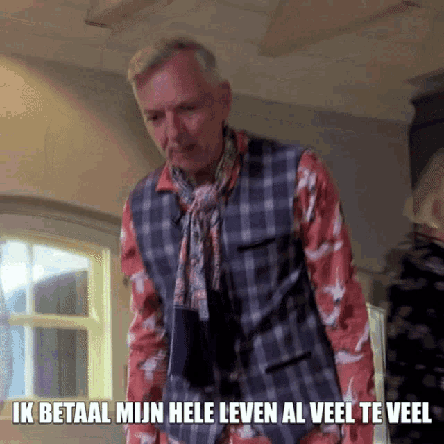 a man in a plaid vest and scarf is standing in front of a window with the words ik betaal mijn hele leven al veel te veel