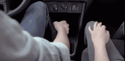 a man and a woman are driving a car and the woman is pressing the brake pedal .