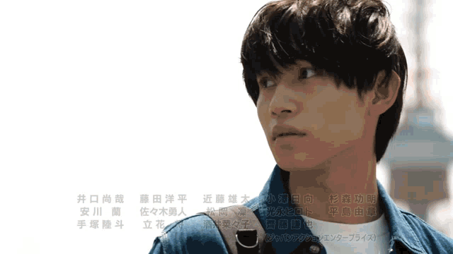 a man in a denim jacket stands in front of a white background with chinese characters