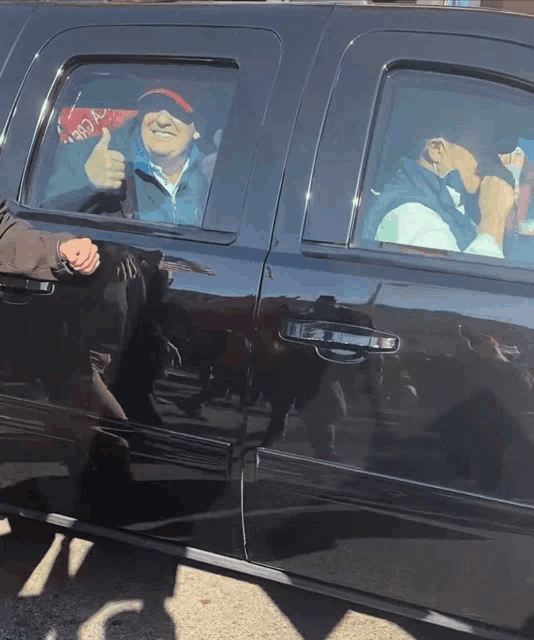 a man giving a thumbs up while sitting in the back of a truck