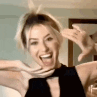 a woman in a black dress is making a funny face with her mouth open and arms outstretched .