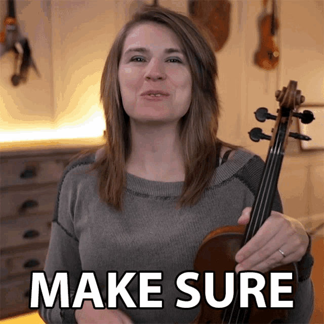 a woman holding a violin with the words make sure behind her