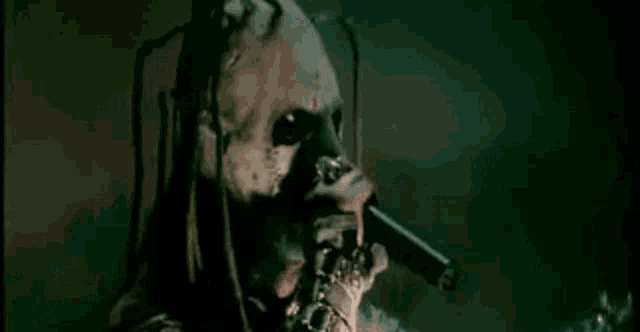 a skeleton is holding a microphone in his hand and singing into it in a dark room .