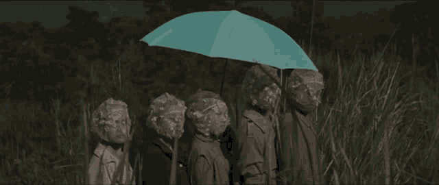 a group of people with plastic bags on their faces holding a blue umbrella