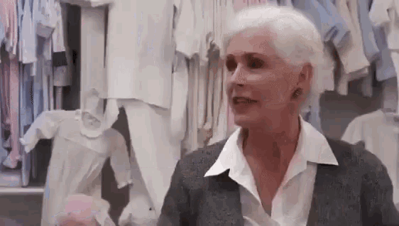 a woman is standing in front of a closet full of baby clothes .