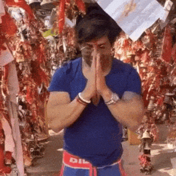 a man in a blue shirt with the word dil on his shorts prays