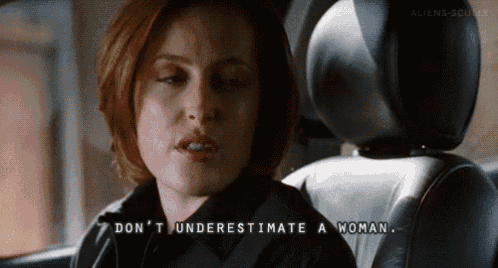 a woman is sitting in the back seat of a car and says " don 't underestimate a woman " .