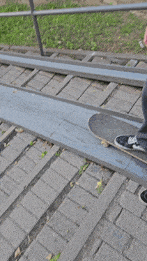 a person is riding a skateboard on a sidewalk with a fence in the background