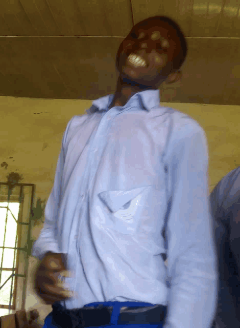 a young man in a blue shirt is smiling with his hands on his hips