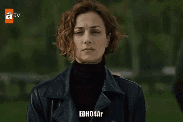 a woman wearing a black turtleneck and a black leather jacket with edh04ar on the bottom
