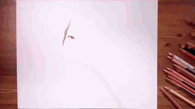 a drawing of a person 's face is on a piece of paper next to some colored pencils