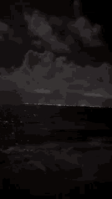 a dark night sky over the ocean with a few lights visible
