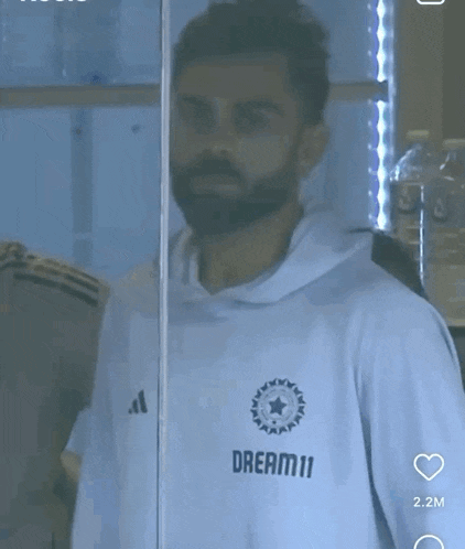 a man with a beard wearing a white shirt that says dream 11