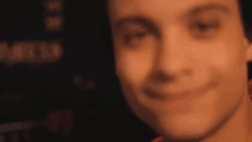 a close up of a person 's face with a blurry background and a smile .