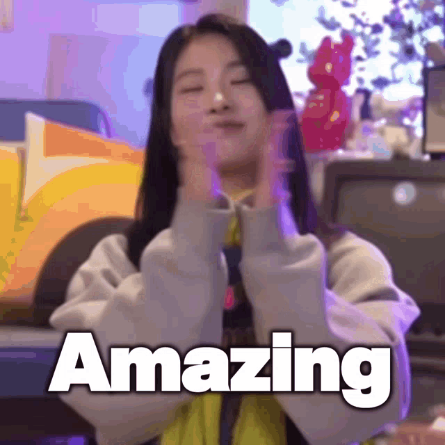 a woman is making a heart shape with her hands and the word amazing is written above her