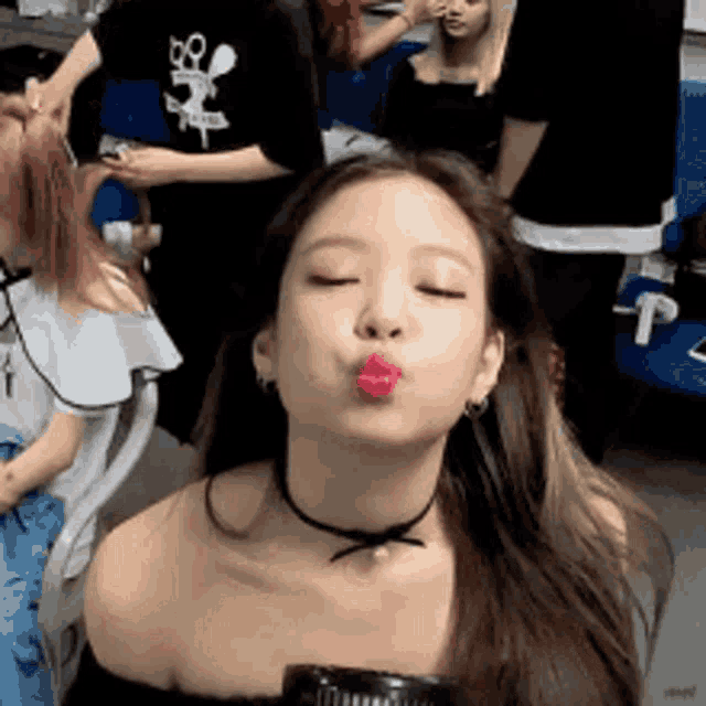 a woman is blowing a kiss with her eyes closed